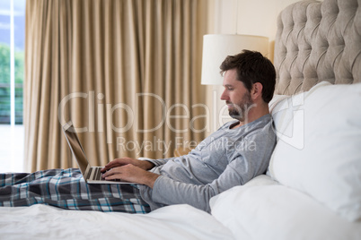 Man using laptop in bed