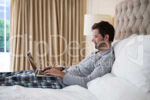 Man using laptop in bed