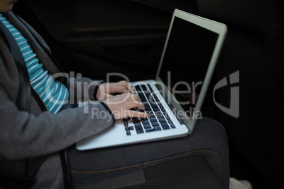 Teenage girl using laptop in the back seat of car