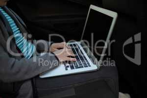 Teenage girl using laptop in the back seat of car