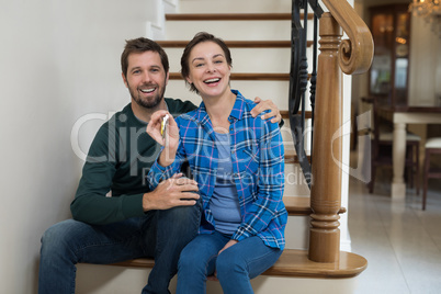 Couple holding house key while sitting on stairs