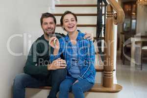 Couple holding house key while sitting on stairs