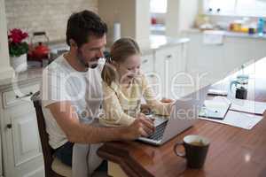 Father and daughter working on laptop