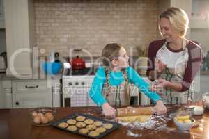 Happy mother and daughter having fun while preparing cookies in kitchen