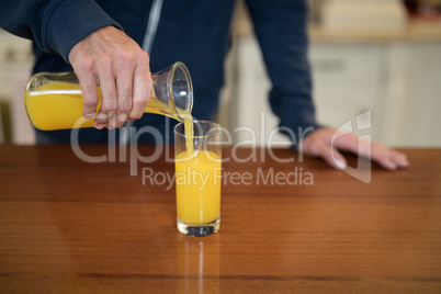 Man pouring juice in the glass in the kitchen