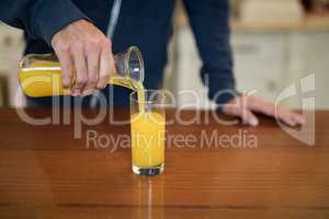 Man pouring juice in the glass in the kitchen