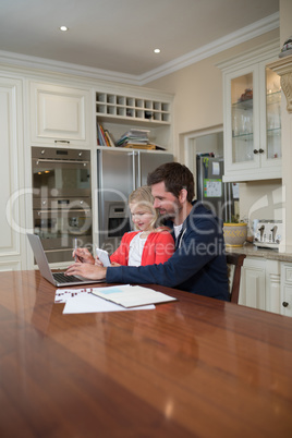 Father and daughter working on laptop