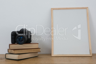 Picture frame, books and digital camera on table