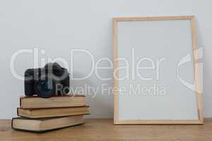 Picture frame, books and digital camera on table