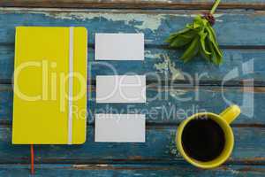 Blank visiting cards, diary, flora and black coffee on wooden plank