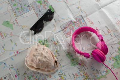 Sunglasses, headphones and seashell on map