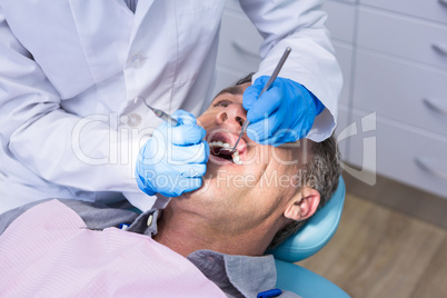 Dentist giving dental treatment to man at medical clinic