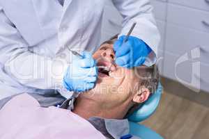 Dentist giving dental treatment to man at medical clinic