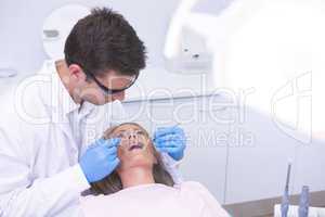 High angle view of dentist holding equipment while examining woman