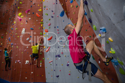 Confident athletes and trainer climbing wall in club