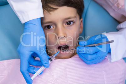 Dentist holding medical equipment while examining boy