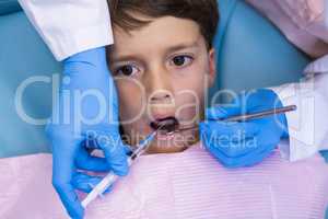 Dentist holding medical equipment while examining boy
