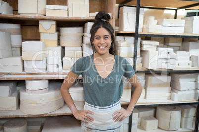 Female potter standing with hands on hip in pottery workshop