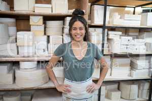 Female potter standing with hands on hip in pottery workshop