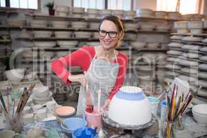 Portrait of female potter painting bowl