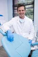 Portrait of dentist standing by chair