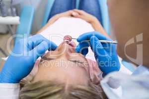 Patient lying on bed while dentist examining at clinic