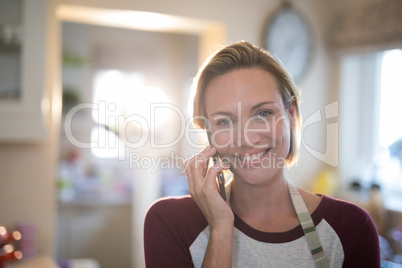 Woman talking on mobile phone in the kitchen at home