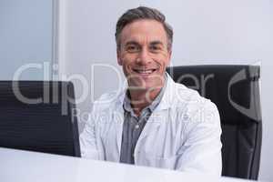 Portrait of dentist sitting by computer at table