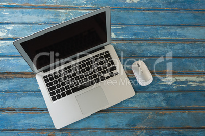 Laptop and mouse on wooden table