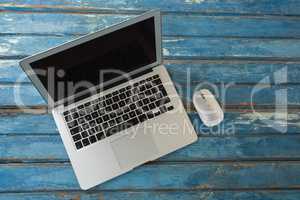 Laptop and mouse on wooden table