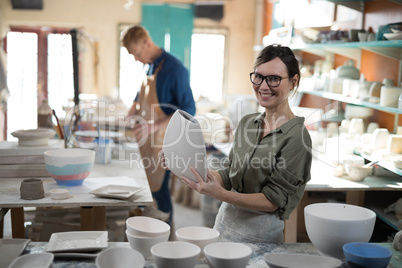 Portrait of female potter checking craft product