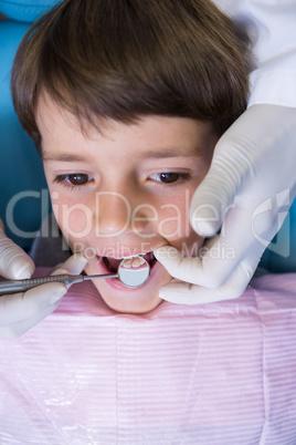 High angle view of dentist holding equipment while examining boy
