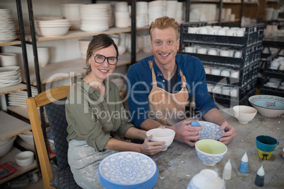 Male and female potter decorating bowl