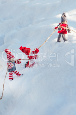 wooden dolls on a snowy slope clinging to a rope