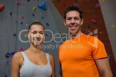 Portrait of confident athletes against climbing wall in gym