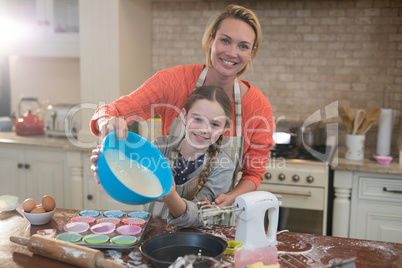 Mother and daughter preparing cup cake in kitchen