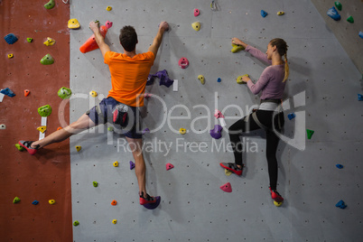 Rear view of athletes rock climbing in club