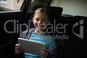 Teenage girl using digital tablet in the back seat of car