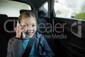 Teenage girl talking on mobile phone in the back seat of car