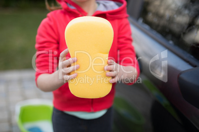 Teenage girl holding a sponge on a sunny day