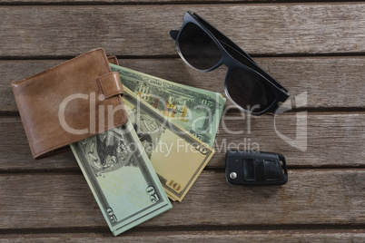 Sunglasses, wallet and currency note on wooden plank