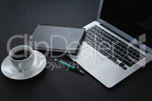 Pen, organizer, black coffee and laptop on black background