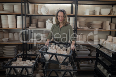 Female potter holding cups in crate