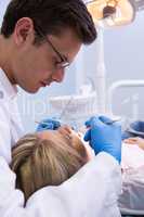 Close up dentist examining woman with dental equipments