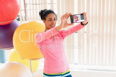 Woman taking selfie with mobile phone in the gym