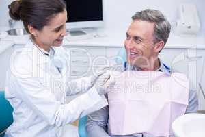 Happy dentist holding tool while looking at man