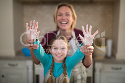 Mother and daughter showing hands in kitchen