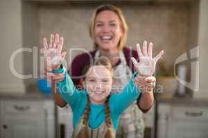 Mother and daughter showing hands in kitchen