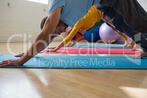 Instructor with students practicing downward facing dog pose at yoga studio