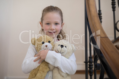 Young girl standing with soft toys at home